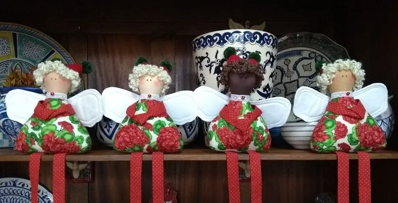 Quatro anjos com roupas verdes e vermelhas e asas brancas.