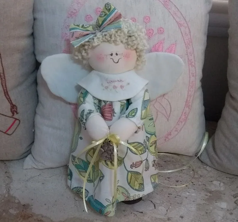 Anjo de cabelos claros e vestido estampado em tons de verde.