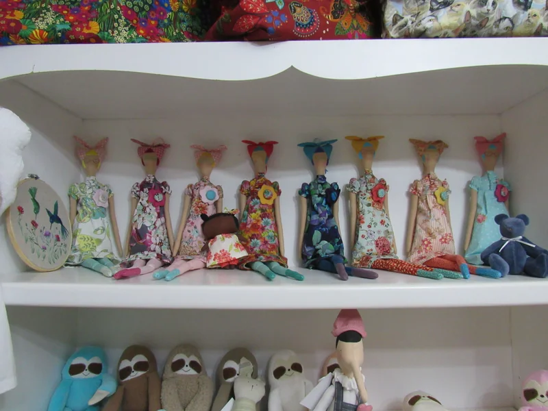 Prateleiras do atelier com gatos de pernas compridas, bonecas e preguiças.