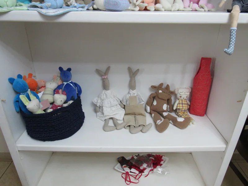Prateleira com coelhos, bichos de tecido e pequenos objetos de trabalho.