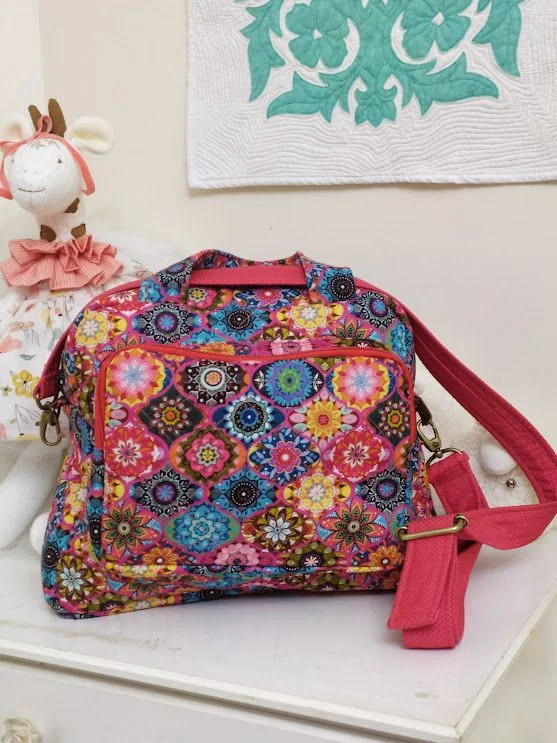 Bolsa de tecido colorido com alça e detalhes rosa.