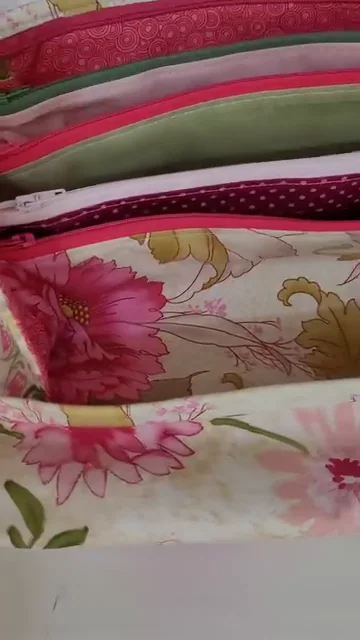 Bolsa organizadora aberta, com bolsos em tecidos florais e zíperes.