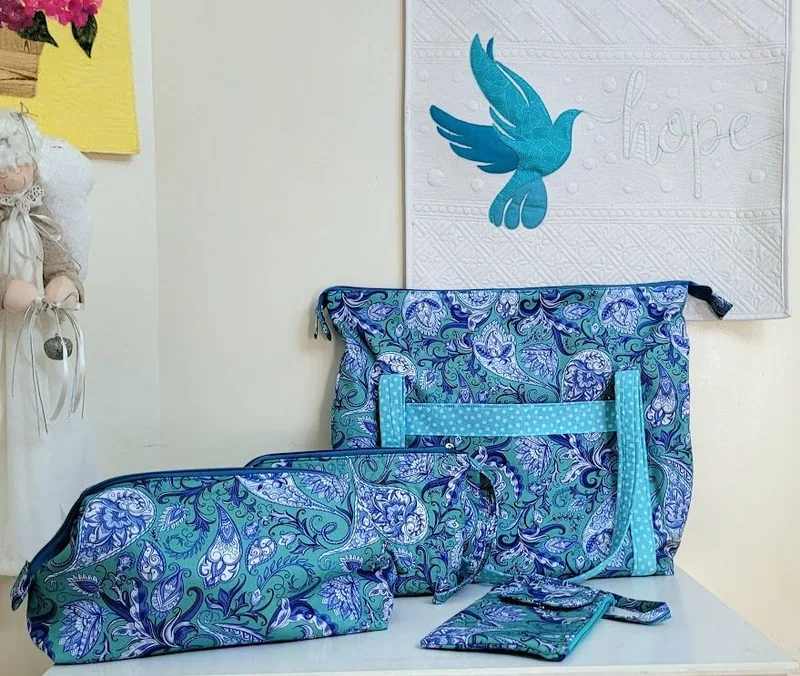 Conjunto de bolsa e nécessaires em tecido estampado azul, verde e lilás.