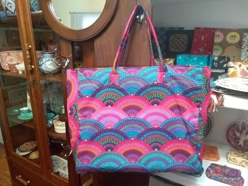 Bolsa de ombro com estampa de arcos em rosa, azul e roxo.