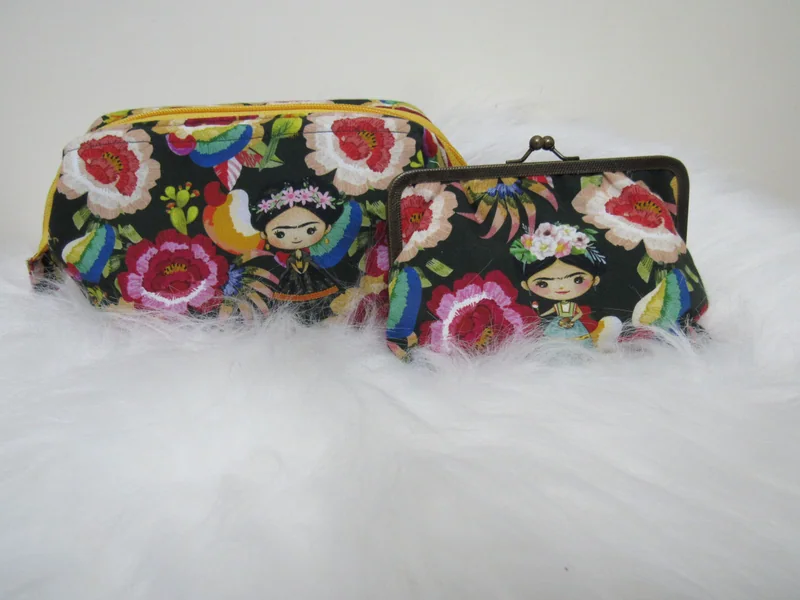 Duas bolsas com flores e retratos de Frida estampados sobre fundo escuro.