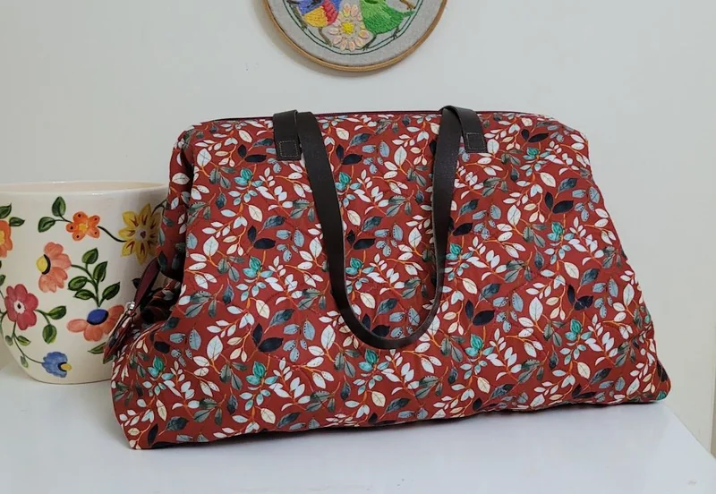 Bolsa grande em tecido vermelho estampado com flores e folhas.