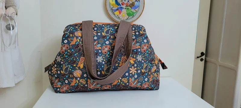 Bolsa de tecido azul com estampa floral e alças marrons.