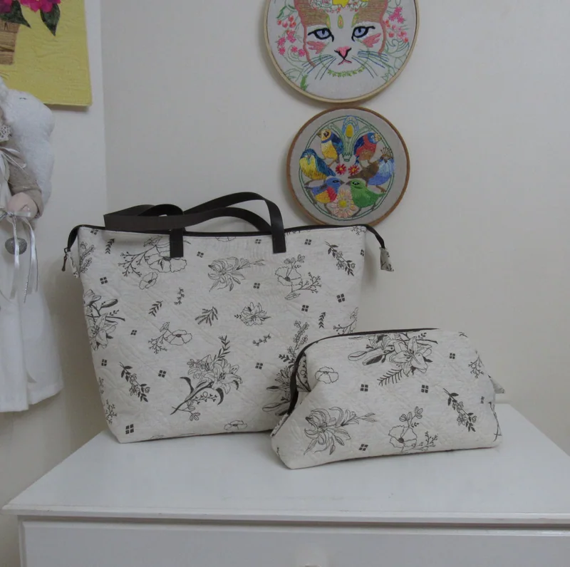 Bolsa e nécessaire claras com desenhos em preto.