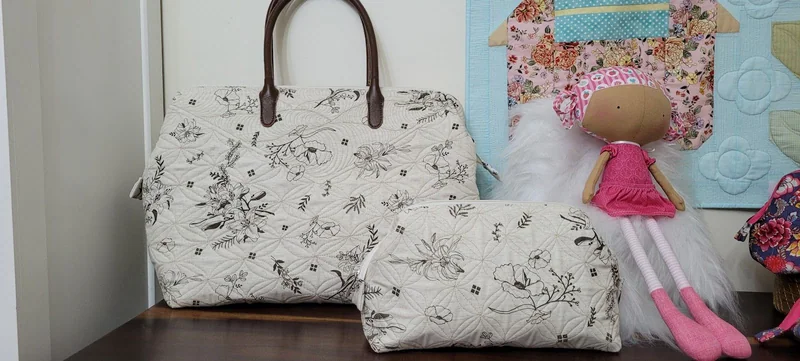 Bolsa de alças marrons e nécessaire com a mesma estampa em preto e branco.