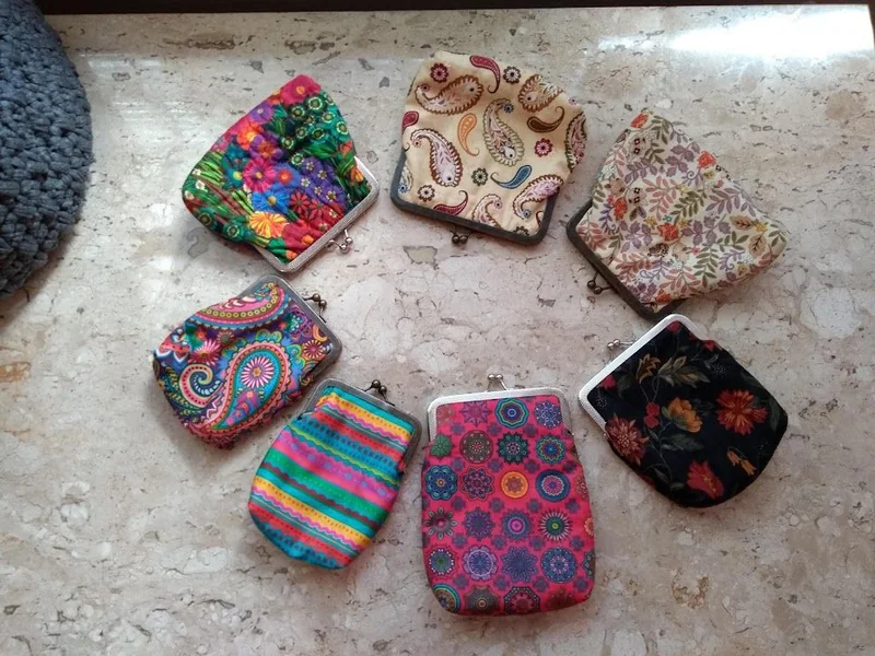 Pequenos porta-moedas abertos, mostrando tecidos de diversas estampas.
