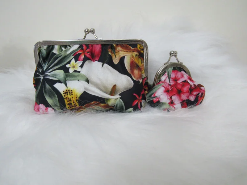 Duas bolsinhas de fecho de metal, uma com flores claras e outra com flores rosa.