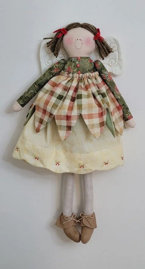 Boneca de tranças com vestido xadrez em verde e vinho e avental bege.