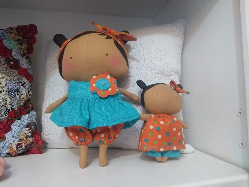 Duas bonecas com vestidos azul e laranja, em tamanhos diferentes.