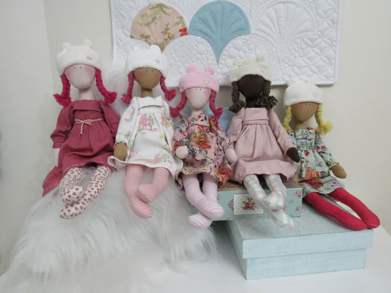 Bonecas com toucas e diferentes combinações de tecidos, reunidas no atelier.
