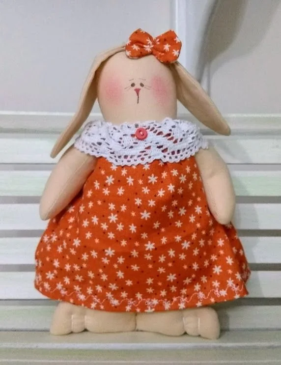 Coelha com vestido laranja de bolinhas brancas e gola rendada.