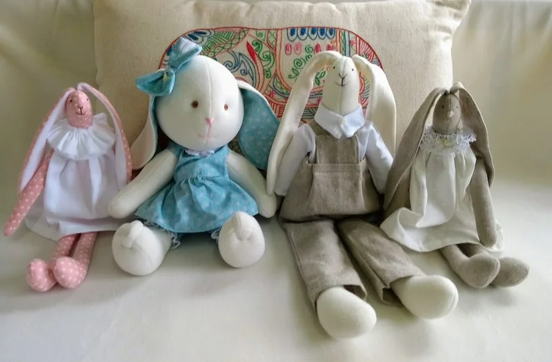 Coelhos com roupas em rosa, azul e tons naturais.