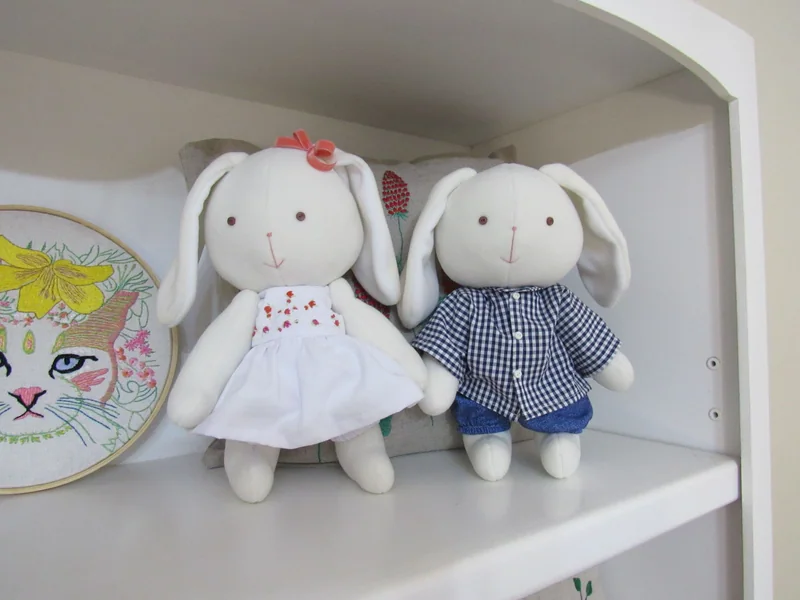 Dois coelhos com vestido branco e camisa xadrez azul.