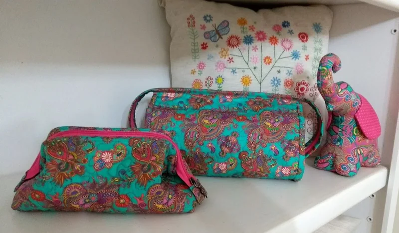 Bolsa e nécessaire em tecido floral de tons verdes e vermelhos.