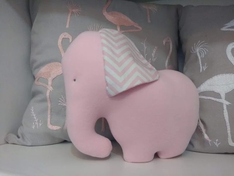 Elefante rosa com orelha de zigue-zague cinza e branco.