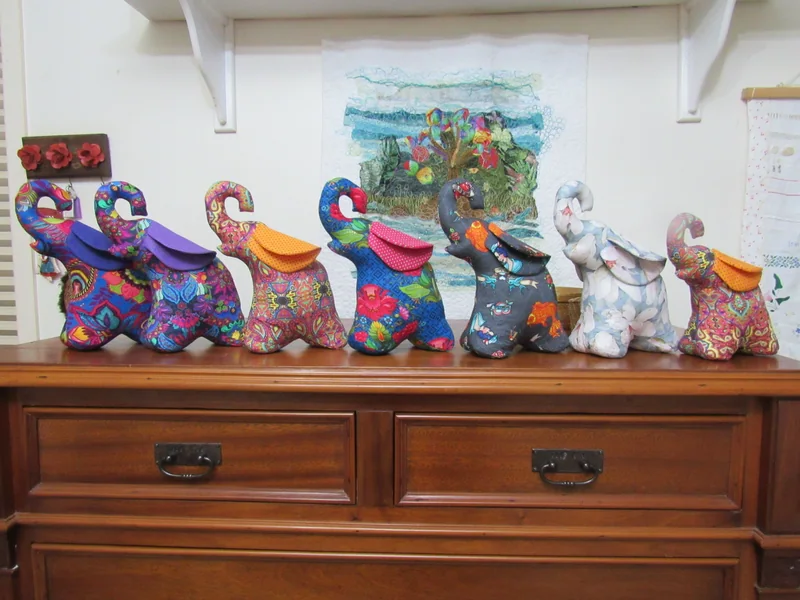 Elefantes de tecido estampado reunidos sobre um móvel no atelier.