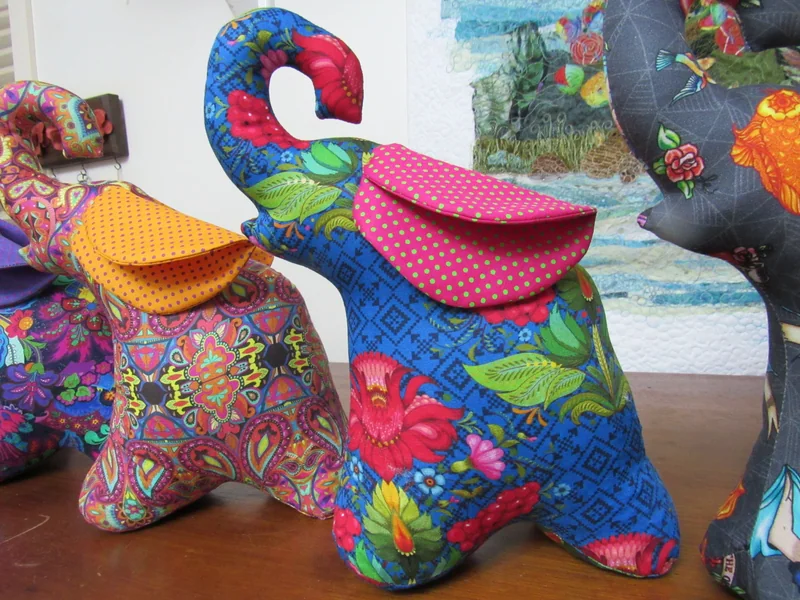 Elefante de estampa colorida com orelha rosa.