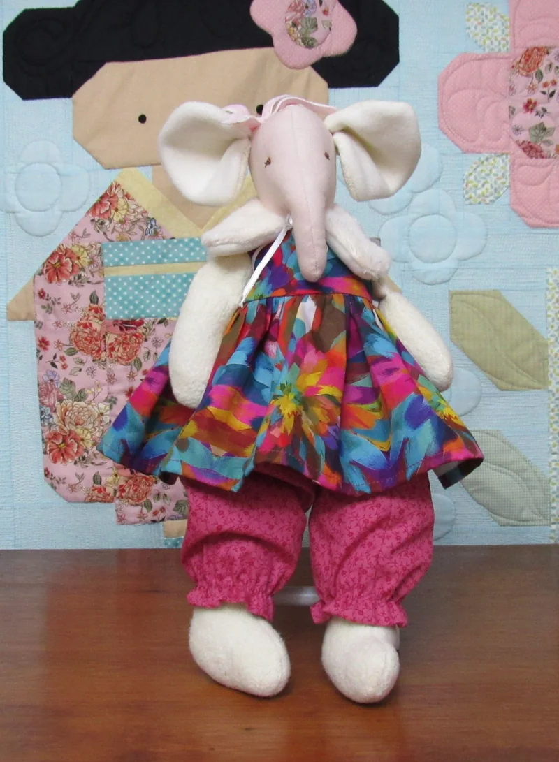 A elefantinha com um vestido de flores coloridas e calças rosa.
