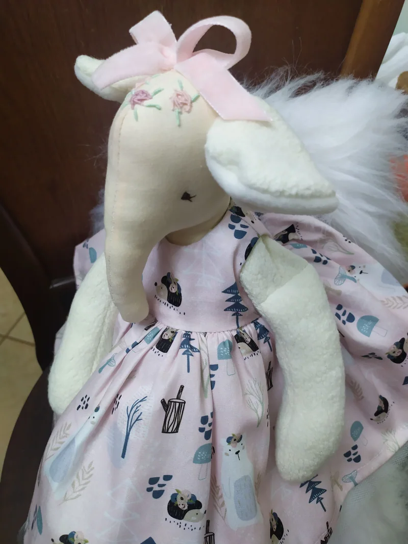 Elefantinha com vestido de pequenos desenhos e laço rosa na cabeça.