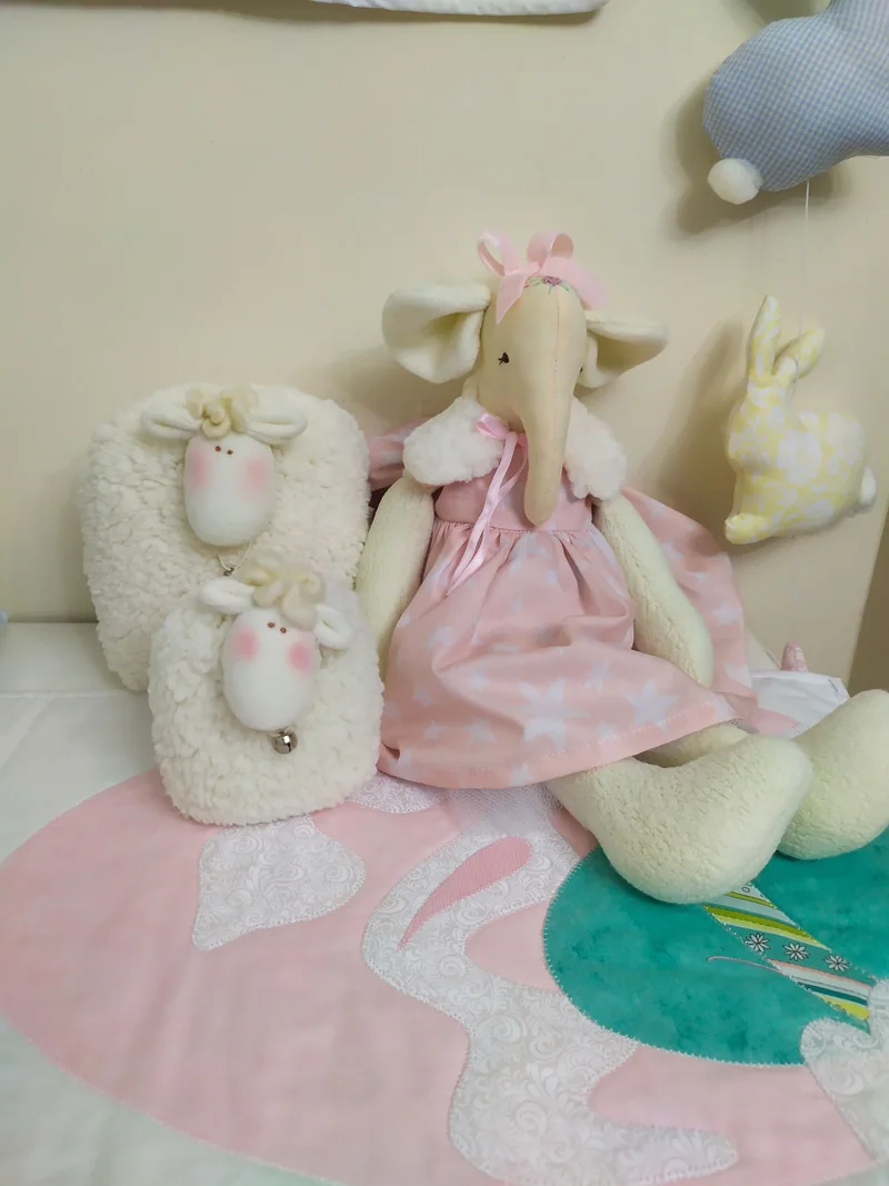 Elefantinha de vestido rosa ao lado de ovelhinhas claras.