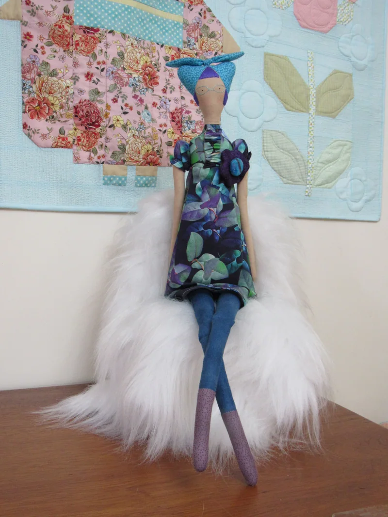 Gato azul com vestido de flores e pernas roxas.