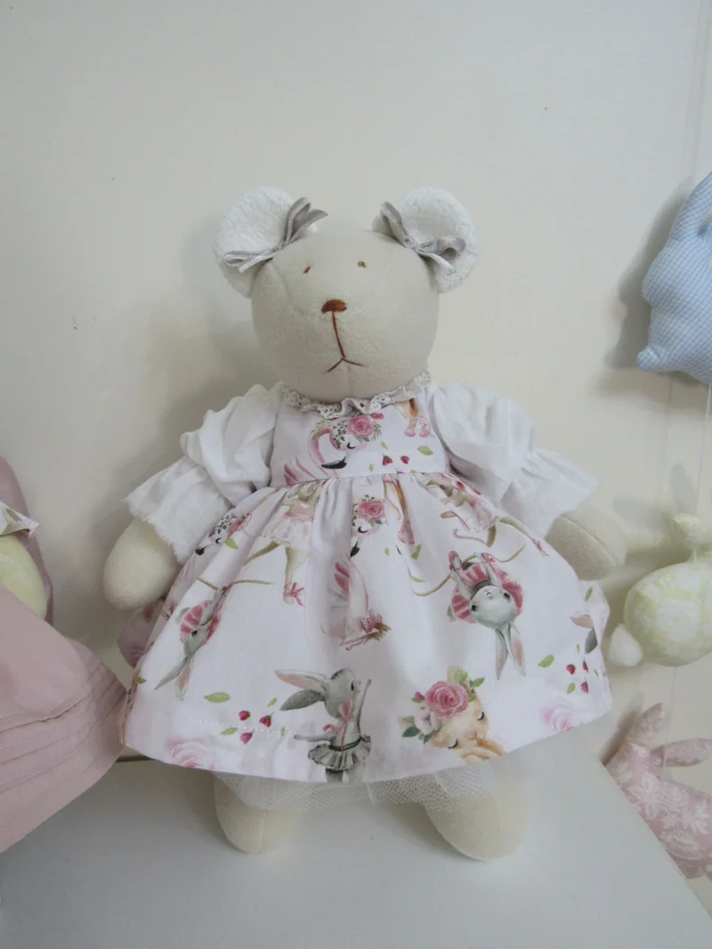 Ursinha clara com vestido de mangas curtas e estampa floral.