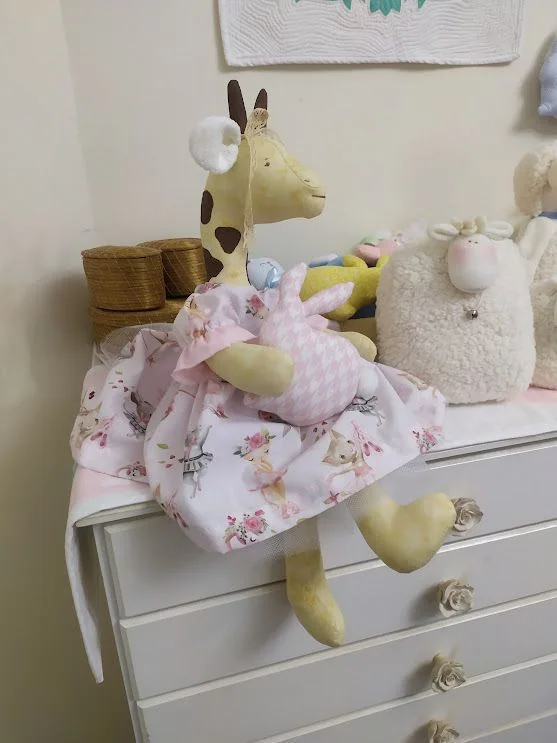 Girafa sentada com vestido floral em rosa, azul e verde.