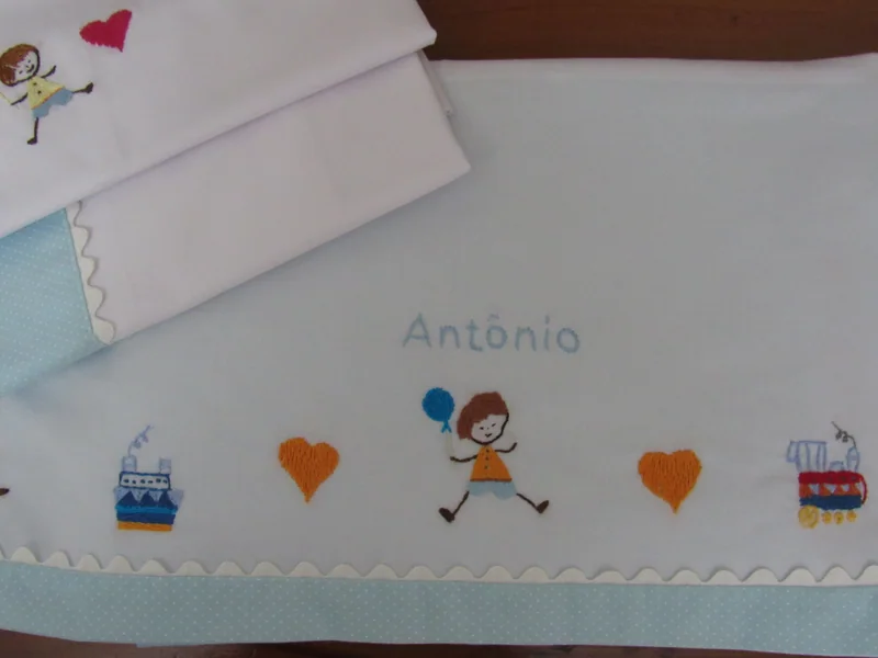 Detalhe dos personagens, dos corações e do nome Antônio bordados no lençol.