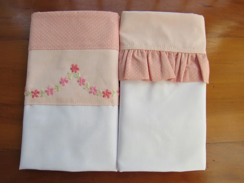 Peças de um jogo de lençol com acabamento rosa.