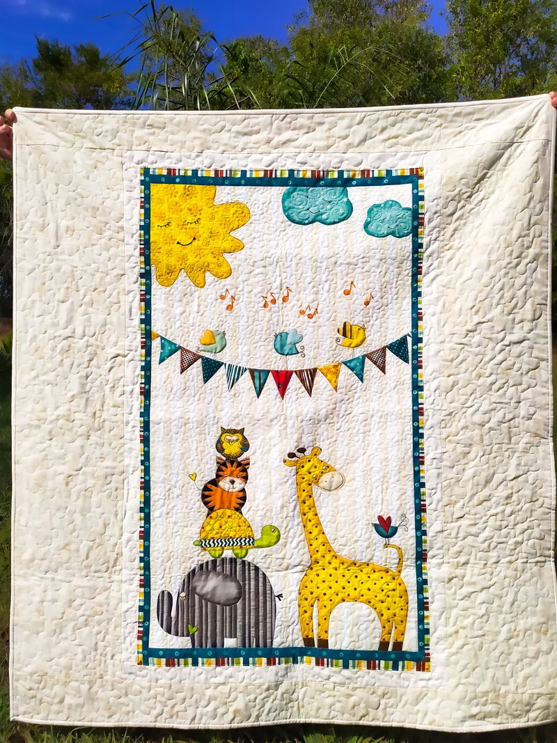 Manta clara pendurada ao ar livre, com painel de girafa, elefante, gato, sol e bandeirinhas.