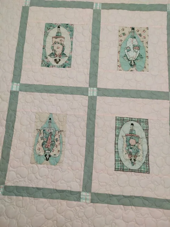 Manta clara com seis blocos estampados e molduras verdes.