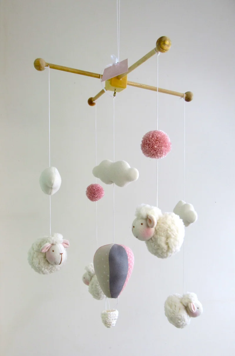 Móbile com balões e nuvens em branco, rosa e cinza.