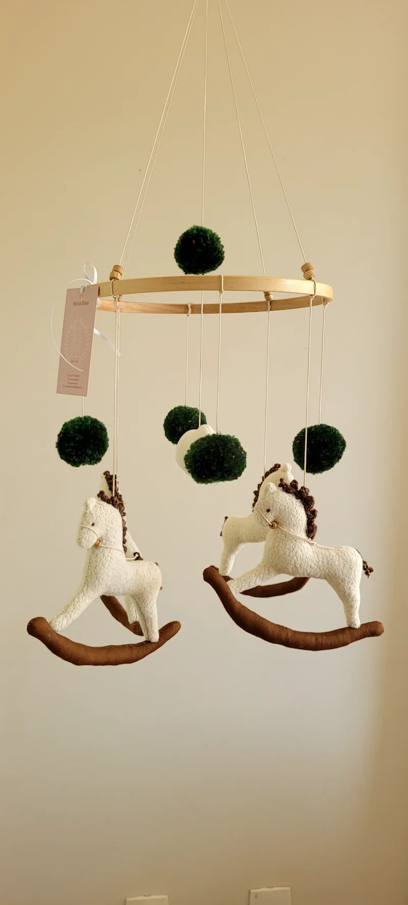 Outro móbile do mesmo modelo, com dois cavalos de balanço e pompons verde-escuros.