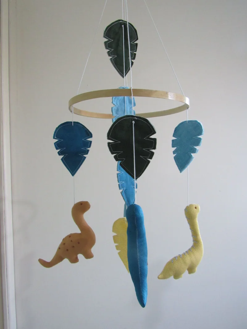 Variação em aro de madeira, com dinossauros e folhas em azul, verde e amarelo.