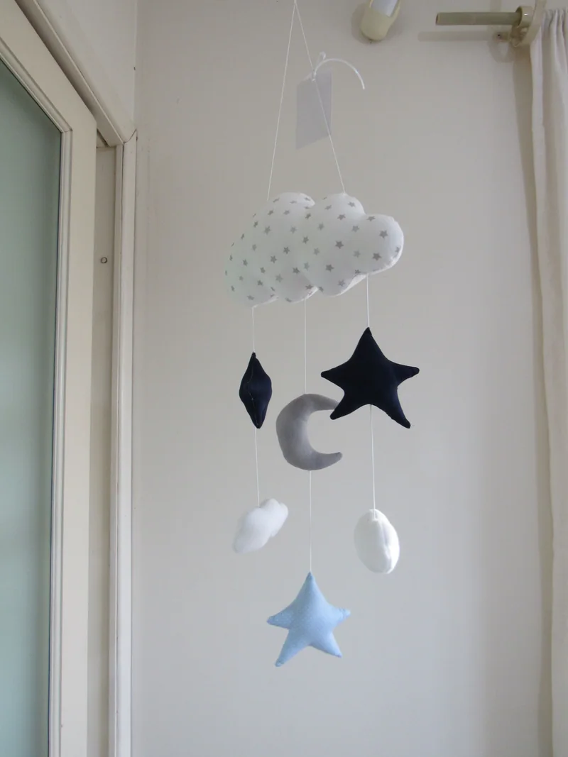Móbile com nuvem branca, estrelas azuis e lua clara.