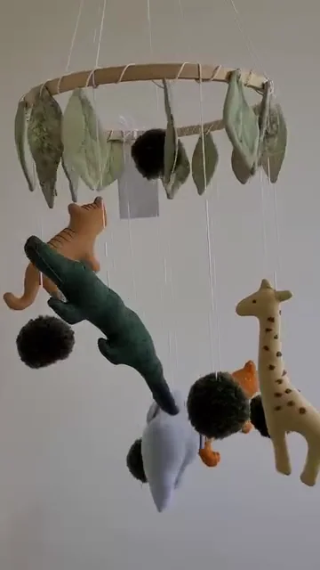 Animais de safári e folhas pendurados em um aro de móbile.