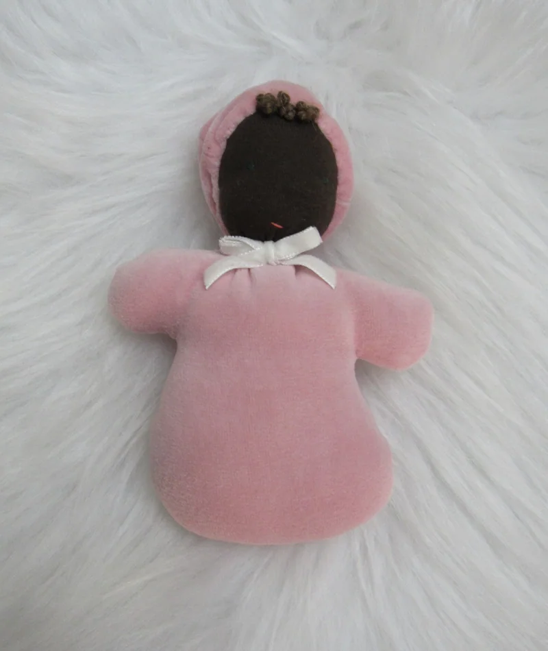 Naninha de pele marrom com capuz e roupa rosa.