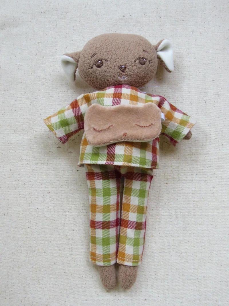 Bichinho marrom com pijama xadrez em vermelho, verde e branco.