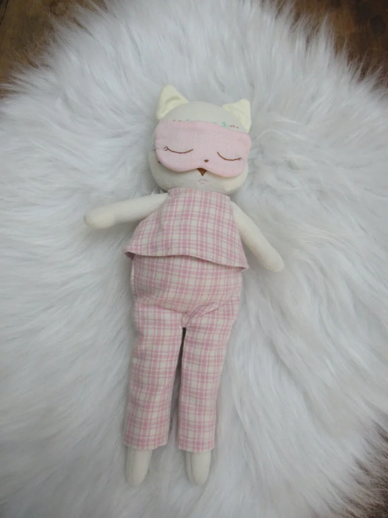 Gatinho com pijama rosa e máscara sobre os olhos.