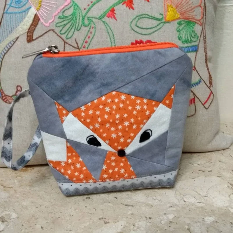 Nécessaire cinza com raposa laranja em patchwork e zíper laranja.