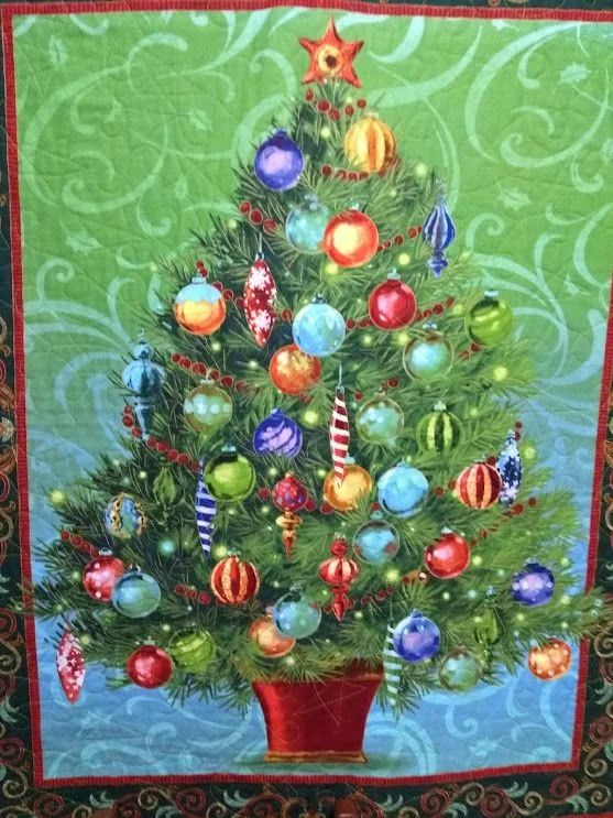 Painel verde com árvore de Natal de tecido e enfeites coloridos.