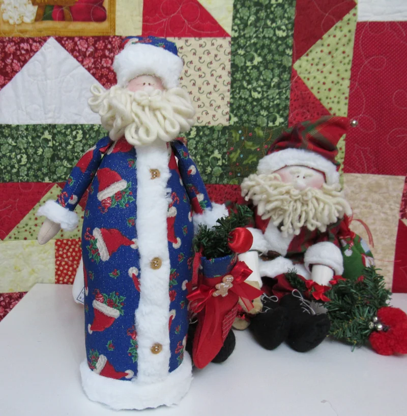 Papai Noel alto de roupa azul ao lado de um boneco menor.