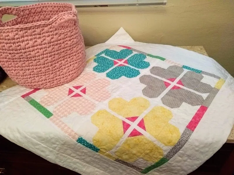 Patchwork com flores geométricas em várias cores e costuras de quilting.