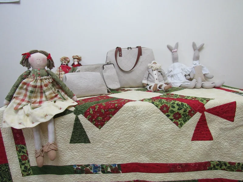 Peça de patchwork de laços vermelhos e verdes aberta sobre uma mesa no atelier.