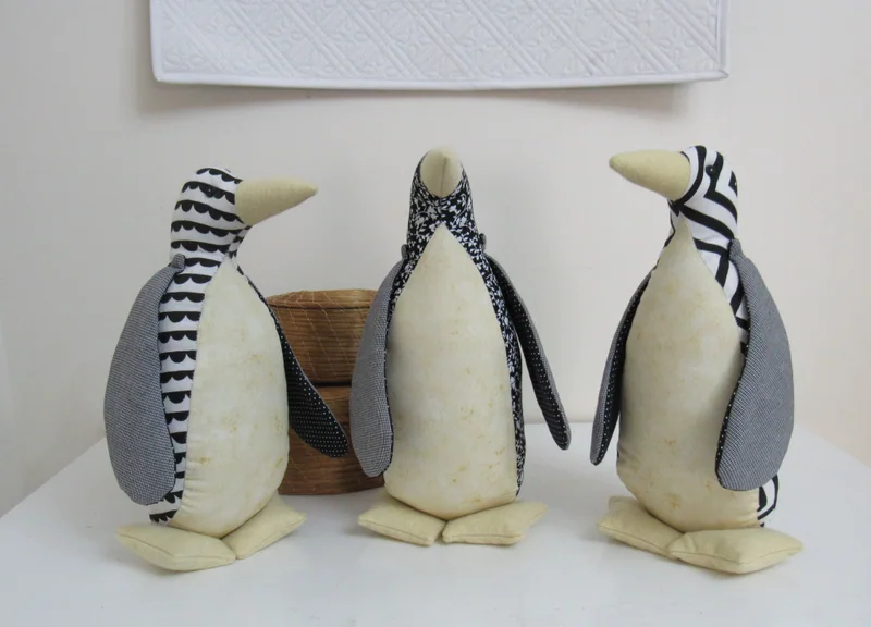 Três pinguins de tecido com estampas em preto e branco.
