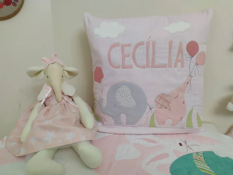 Quillow rosa com o nome Cecília, elefante e girafa aplicados em tecido.